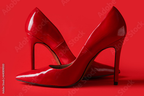 Stylish red high heels on color background