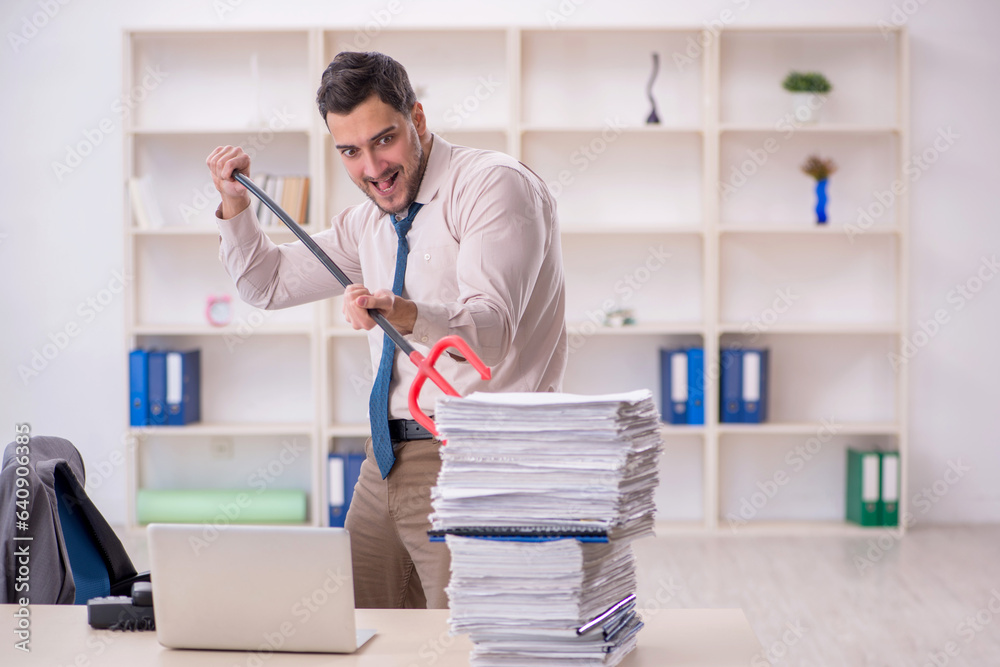 Young male employee unhappy with excessive work in the office Young male employee unhappy with excessive work in the office