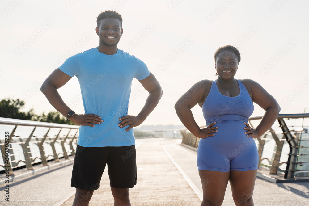 African American man and woman in sportswear after training outdoors, standing, looking at camera