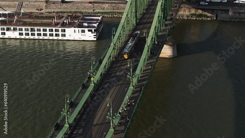 Tracking of tram passing over nice historic bridge at golden hour. Aerial view of transport infrastructure and public transportation. Budapest, Hungary
