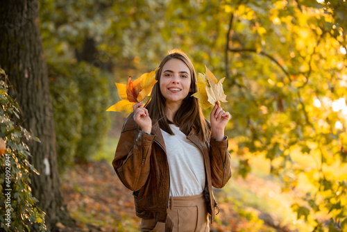 Young woman in autumn park. Warm sunny weather. Fall concept. Hello autumn. Happy woman with autumn yellow leaves outside. Beautiful autumn fall time in nature.