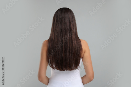 Woman with damaged messy hair on grey background, back view