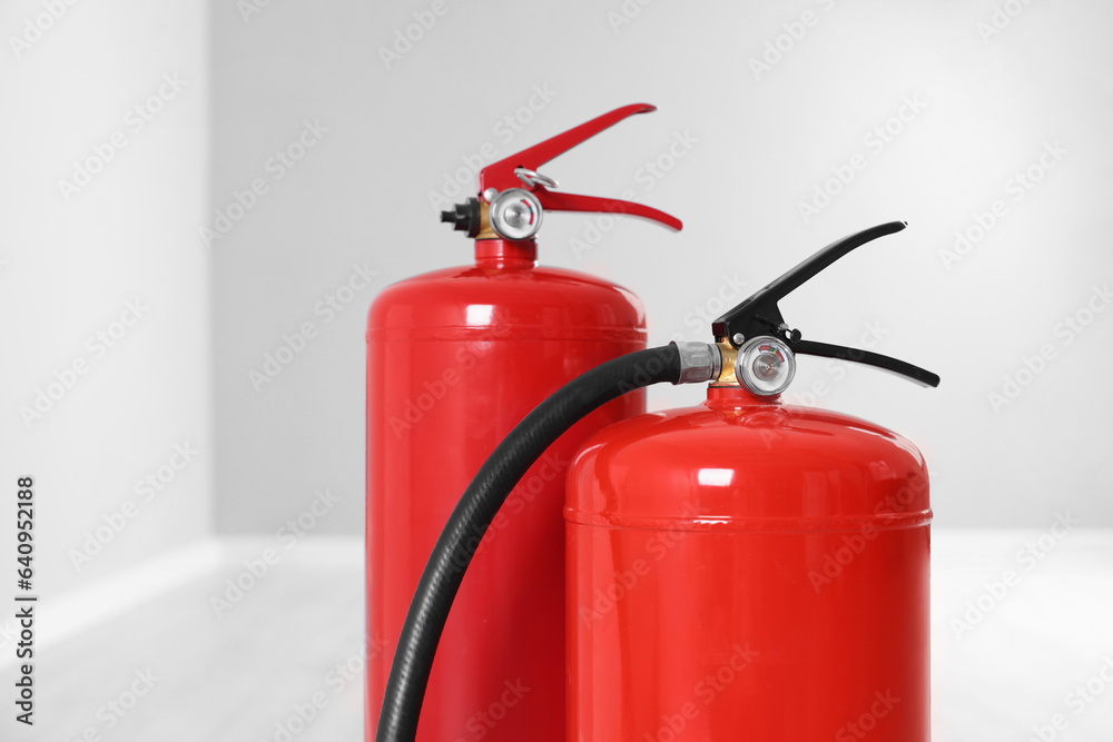 Two red fire extinguishers indoors, closeup view Two red fire extinguishers indoors, closeup view
