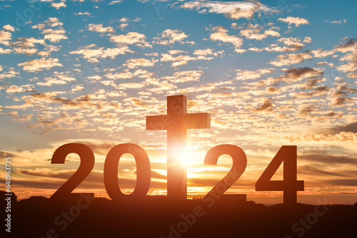 Photographie Silhouette of Christian cross with 2024 years at sunset background