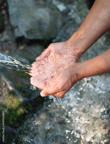 Hands, water splash and washing in nature. Man scoops up water with his hands to drink. Fresh water of mountain spring