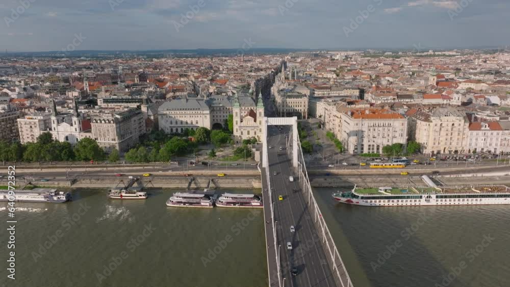 Aerial view of metropolis at golden hour. Vehicles driving on bridge over Danube and on waterfront. Budapest, Hungary Aerial view of metropolis at golden hour. Vehicles driving on bridge over Danube and on waterfront. Budapest, Hungary