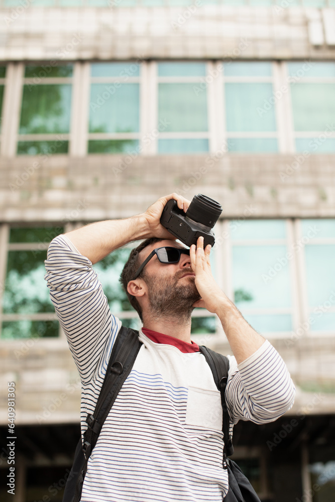 A young man, a traveler, taking pictures with a digital camera, on the street, in a city in Spain. A young man, a traveler, taking pictures with a digital camera, on the street, in a city in Spain.
