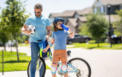 daddy and son child developing his childhood on bicycle outdoor together