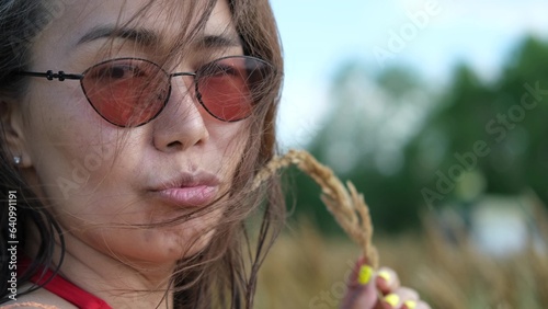 Portrait of a beautiful asian woman on the background of dry long grass while relaxing in summer. slow motion portrait. photo