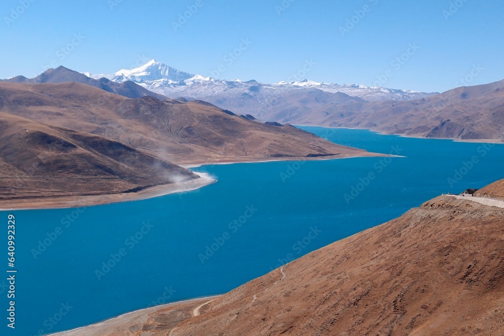 Lake Yamdrok Tso in Tibet is a revered azure gem, symbolizing wisdom and compassion. Embraced by serene majesty, it's surrounded by snow-capped peaks.
