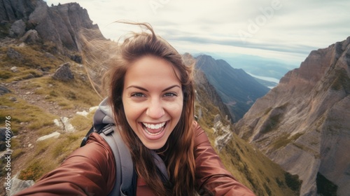 Young woman traveler taking selfie on hills with mountains Happy and smiling hiker taking a selfie on the top of the mountain.