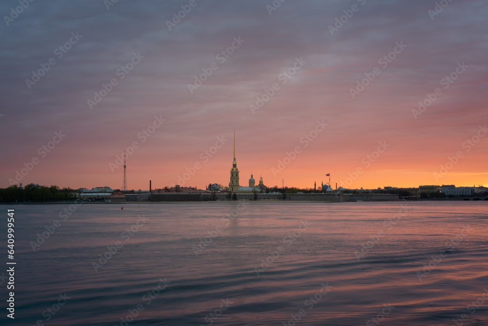 View of the Peter and Paul Fortress and the Neva River against a pink dawn sky with clouds on a sunny spring morning, St. Petersburg, Russia