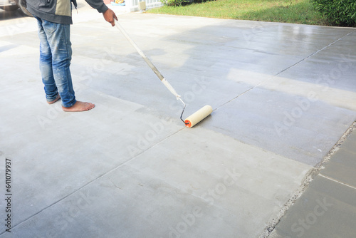 Worker and renovation work. To using roller painting mortar cement or finishing material for repair crack, skim coat or improvement surface of concrete pavement floor or slab for driveway or garage.