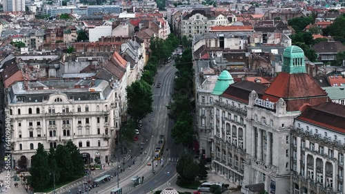 Modern tram driving on street between rows of old multistorey buildings in city. Aerial view of urban borough. Budapest, Hungary