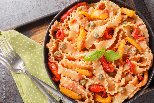 Ribbon-shaped Italian pasta mafaldine cooked with creamy tomato sauce and bell peppers close-up in a bowl on the table. horizontal top view from above photo