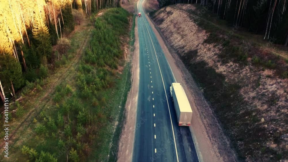 Heavy truck is carrying cargo on the highway in a beautiful area at dawn. Lorry rides through the countryside with beautiful landscape at background. International Trade, Cargo Delivery, Cargo Heavy truck is carrying cargo on the highway in a beautiful area at dawn. Lorry rides through the countryside with beautiful landscape at background. International Trade, Cargo Delivery, Cargo