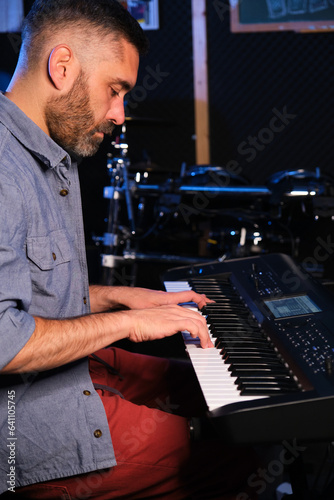 Musician man playing keyboard synthesizer piano in a recording studio. Music production. © Ladanifer