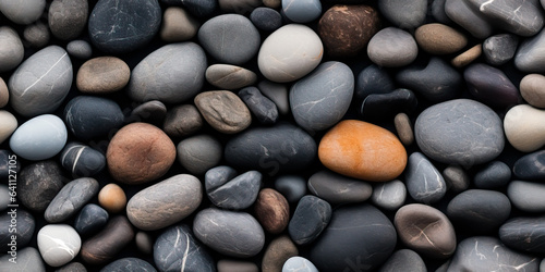 River rocks or stones in a seamless tiled pattern. Naturally polished and rounded river pebbles create a repeating background texture.