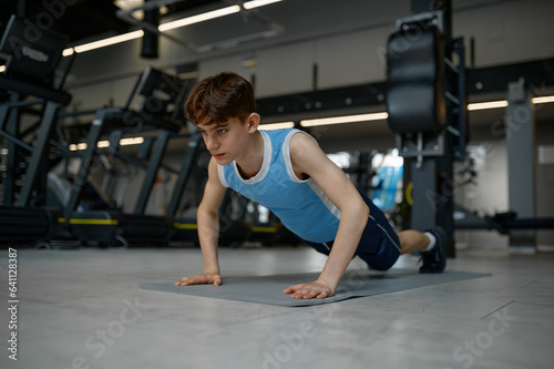 Teenager healthy boy making gymnastics pushup while training at gym