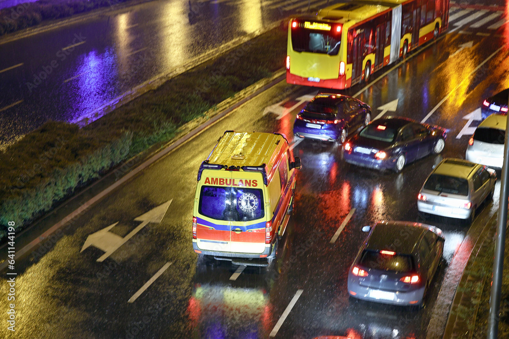 Karetka medyczna ratunkowa w deszczu na sygnale jedzie  na sygnale jedzie wieczorem z pomocą - obrazy, fototapety, plakaty 