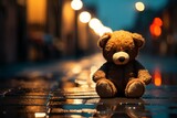 A sad teddy bear sits alone on a rainy night street