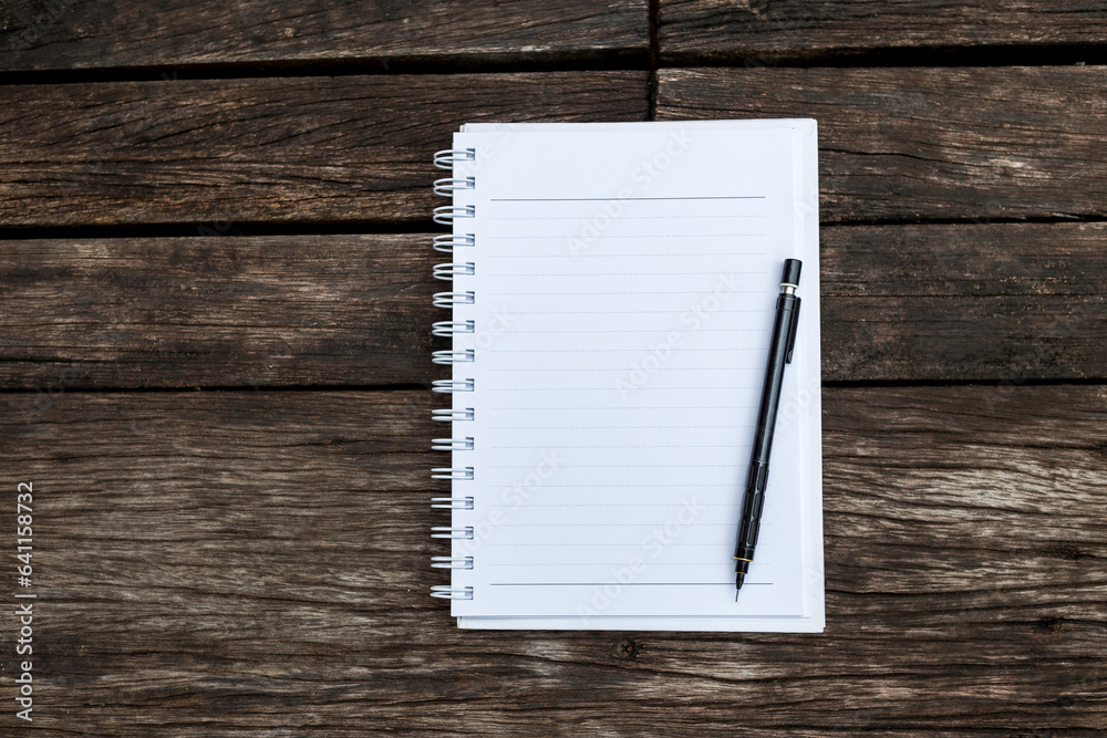 Blank white paper note book with black pencil on old wooden floor background, education industry concept Blank white paper note book with black pencil on old wooden floor background, education industry concept
