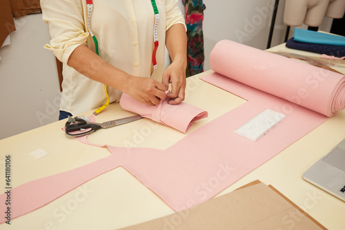 Young Asian female fashion designer examining cloth in her studio 