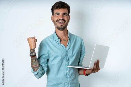 Cheerful cheery content young caucasian man wearing green shirt holding in hands device hobby smm post blog