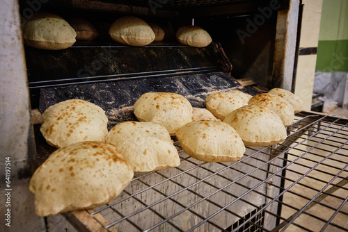 Baking traditional egyptian flatbread aish baladi. Freshly baked pita bread from oven. Traditional egyptian street baker shop. 