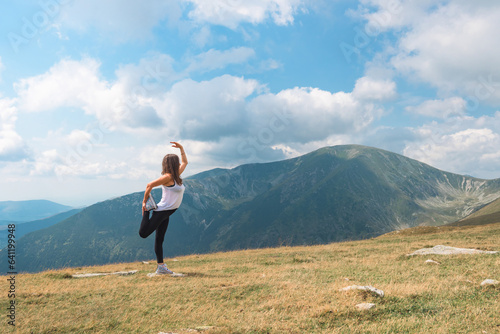 A young and beautiful woman does gymnastics, meditation and yoga exercises in a beautiful mountain setting. Sport and Yoga in nature, in mountain landscapes.