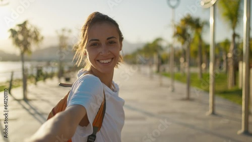 POV first person view young happy Woman traveler walking bay sidewalk and watching sunset or sunrise with mountains and sea view. girl inviting to walk with her, throwing hand to someone. follow me