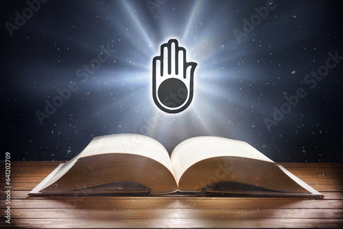 Fotografia Open book on wooden table and Jainism symbol front view