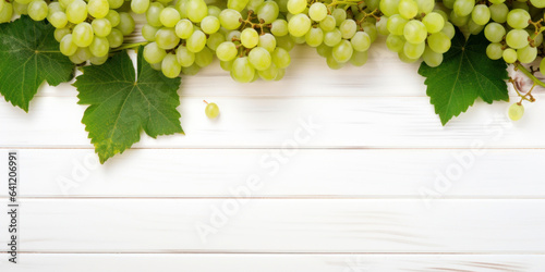 Green juicy grapes on white wooden background.