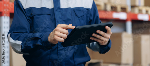 Industry worker use computer tablet in logistic warehouse with cardboard boxes for delivery. Banner online deliver cargo business