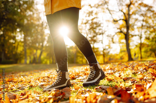 Close-up of feet in hiking boots in a clearing among fallen leaves in a sunny autumn park. Lifestyle concept, outdoor walk.