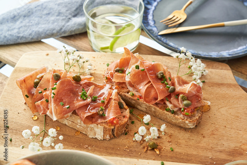 Fototapeta Naklejka Na Ścianę i Meble -  Delicious bruschettas with prosciutto and water glass served on table