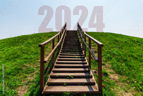 Fototapeta Naklejka Na Ścianę i Meble -  New year concept of 2024. New year future. Numbers at the top of the mountain.Landscape, wooden stairs leading to the top of the mountain, blue sky with letters 2024 on the mountain.