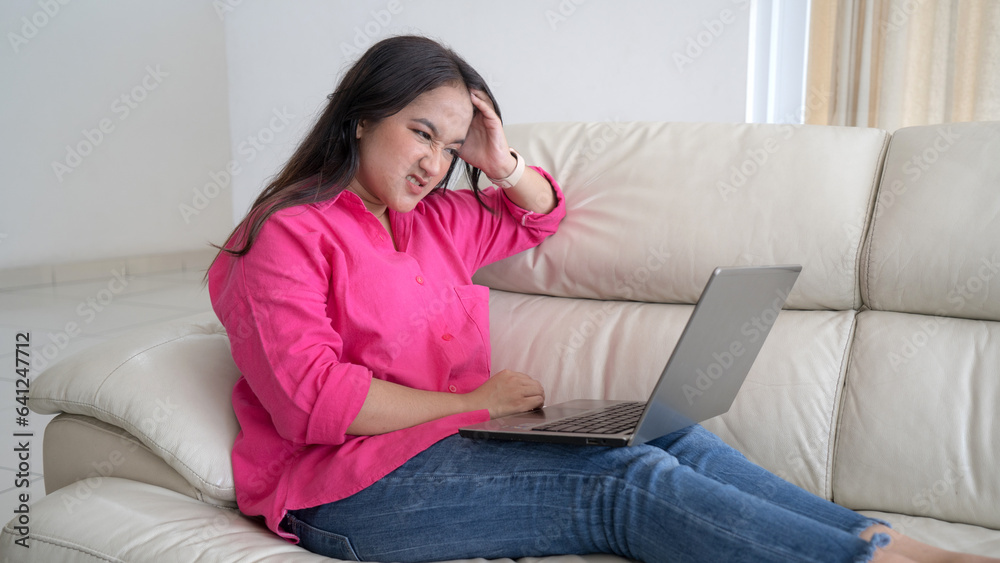 Frustrated sad woman feeling tired worried about problem sitting on sofa with laptop Frustrated sad woman feeling tired worried about problem sitting on sofa with laptop