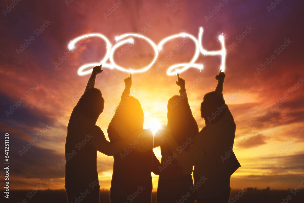 Silhouette rear view of happy business teamwork pointing at new year number 2024 in the sky