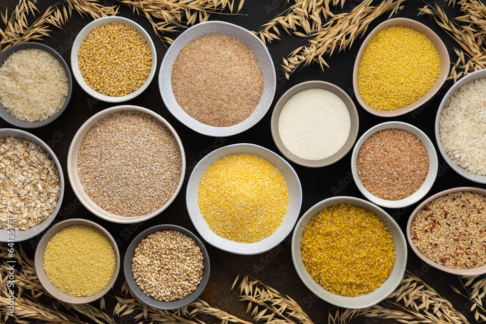 Various grain cereals in bowls, top view on a brown background with bowls of cereals and ears of oats Various grain cereals in bowls, top view on a brown background with bowls of cereals and ears of oats