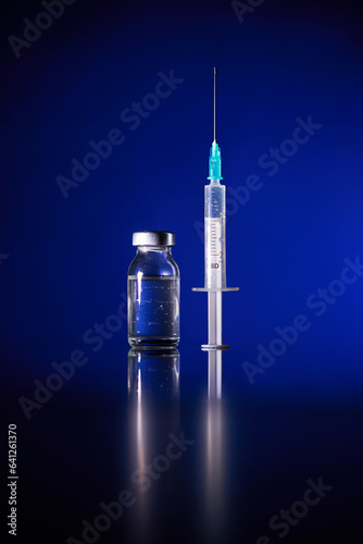 Injection with COVID19 vaccine vial in blue studio