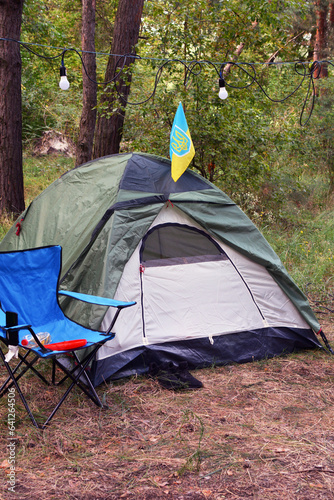  a tent and chairs in a forest with a Ukrainian flag