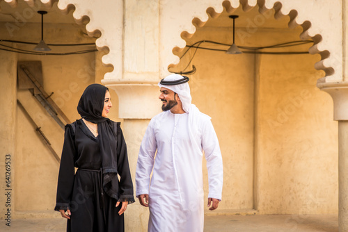 Middle eastern couple of lovers wearing traditional emirati clothing dating outdoors in Dubai - Modern arabian couple meeting and having fun in the city photo