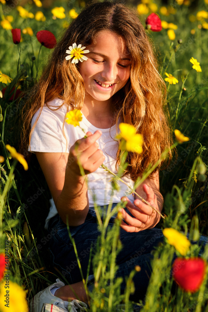Fototapeta premium Smiling girl with flower relaxing in meadow