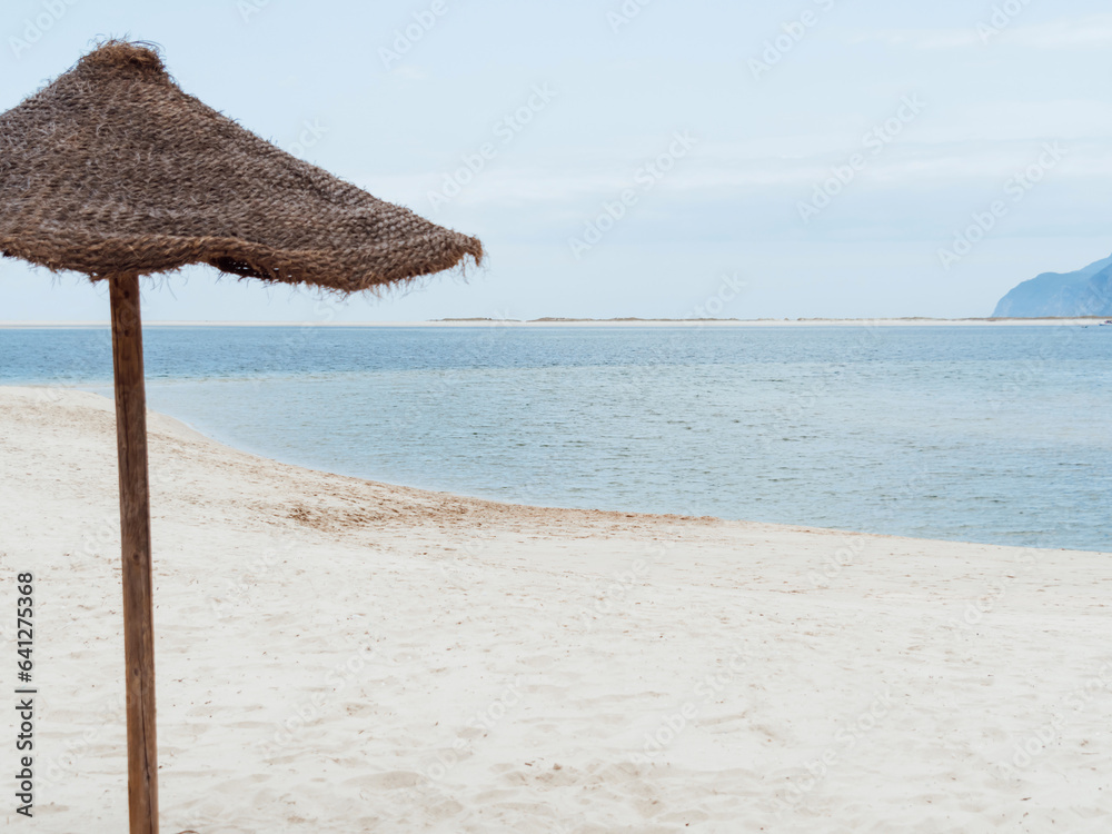 Straw umbrella on empty seaside beach. Beach holiday concept. Straw umbrella on empty seaside beach. Beach holiday concept.