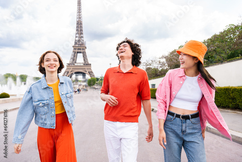 Group of young happy friends visiting Paris and Eiffel Tower - Multiethnic teens bonding outdoors and having fun sightseeing the city photo