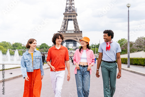 Group of young happy friends visiting Paris and Eiffel Tower - Multiethnic teens bonding outdoors and having fun sightseeing the city photo