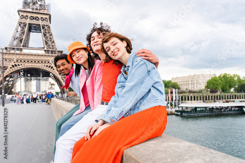 Group of young happy friends visiting Paris and Eiffel Tower - Multiethnic teens bonding outdoors and having fun sightseeing the city photo