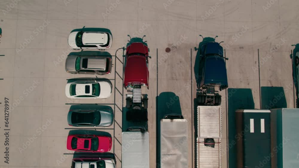 epic top down aerial of a red semi bobtail backing up to a reefer - dry van trailer to hook it up. Proccess of coupling a tractor and trailer. Parking yard with other tractors and trailers parked. USA