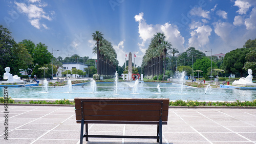 Izmir Alsancak Fuar, palm tree background, beautiful blue sky, bench in the park, fair, free bench in front of the pool photo